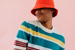 © BONNINSTUDIO/Stocksy - Man wearing colorful clothes and red bucket hat posing on studio