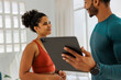 © BONNINSTUDIO/Stocksy - Personal trainer showing digital tablet to smiling client in gym