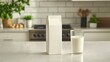 © Tam5 - A Clean Modern Kitchen Scene Featuring an Almond Milk Carton Next to a Glass of Fresh Almond Milk on a Bright Countertop Surrounded by Natural Elements