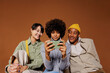 © BONNINSTUDIO/Stocksy - Three young adults sharing fun content on smartphone