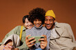 © BONNINSTUDIO/Stocksy - Three friends watching funny video on smartphone