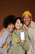 © BONNINSTUDIO/Stocksy - Group of happy friends showing smartphone with blank screen