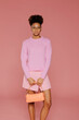 © BONNINSTUDIO/Stocksy - Woman posing and holding orange handbag in studio