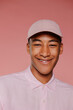 © BONNINSTUDIO/Stocksy - Man wearing pink shirt and cap smiling on pink background