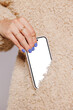 © BONNINSTUDIO/Stocksy - Woman taking smartphone out of her furry pocket