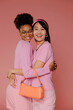© BONNINSTUDIO/Stocksy - Two women embracing and smiling on pink background