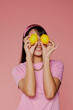 © BONNINSTUDIO/Stocksy - Woman holding lemons over eyes on pink background