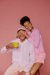 © BONNINSTUDIO/Stocksy - Playful couple having fun holding coffee cup on pink background