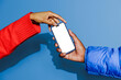 © BONNINSTUDIO/Stocksy - Two people holding smartphone with blank screen on blue background