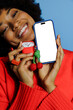 © BONNINSTUDIO/Stocksy - Beautiful young woman holding phone and earphones on blue background