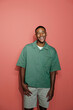 © BONNINSTUDIO/Stocksy - Man smiling wearing green shirt on coral background