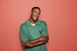 © BONNINSTUDIO/Stocksy - Man smiling with folded arms on coral background