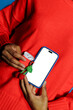 © BONNINSTUDIO/Stocksy - Woman holding smartphone and earphone case with cherry keychain