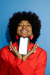 © BONNINSTUDIO/Stocksy - Woman holding smartphone with closed eyes and big smile