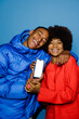 © BONNINSTUDIO/Stocksy - Couple showing smartphone screen on blue background