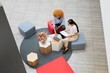 © koganami studio/Stocksy - Top view of coworkers collaborating with laptop and documents