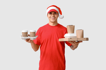 Poster - Delivery man in Santa hat with food order and cups of coffee on white background