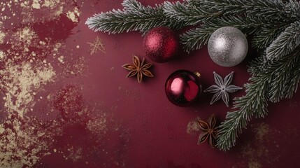 Wall Mural - A flat lay of Christmas decorations, featuring three ornaments, one silver and two red, with a sprig of evergreen and star anise on a deep red background.