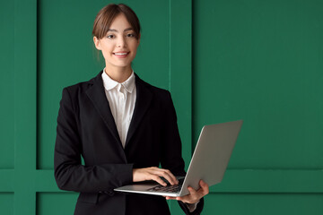 Canvas Print - Beautiful young businesswoman with modern laptop on green background