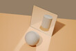 © Juan Moyano/Stocksy - ball in front of a mirror reflects the image of a cylinder