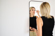 © Guille Faingold/Stocksy - Woman Applying Makeup in a Modern Setting