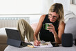 © Guille Faingold/Stocksy - BusinessWoman Sipping Coffee at Home Office while writing