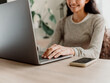 © Marija Savic/Stocksy - Smiling Woman Typing on Laptop in Modern Home Office
