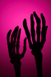 © Tatyana Lavrova/Stocksy - Two Skeleton Hands Reaching Up Towards The Viewer on Magenta backdrop