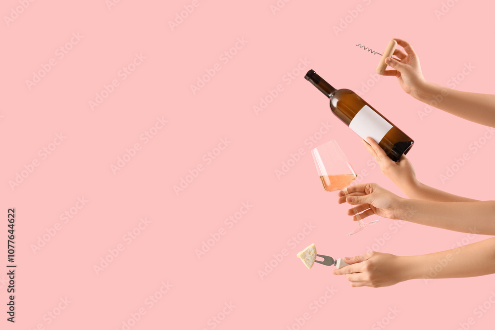 Female hands holding wine, cheese and corkscrew on pink background