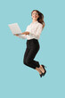 © Pixel-Shot - Young businesswoman with laptop jumping on blue background