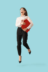 Canvas Print - Shocked businesswoman with folders jumping on blue background