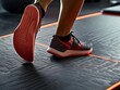 © Vader Stocker - Close-up of a Foot in a Red and Gray Sneaker Running on a Treadmill