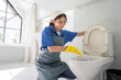 © Kawee - Asian young beautiful female cleaner worker cleaning toilet in restroom.