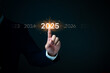 © khunkornStudio - A hand highlights '2025,' representing a milestone or future goal.