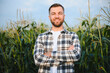 © Serhii - Yong handsome agronomist in the corn field and examining crops before harvesting