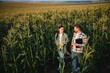 © Serhii - irrigation corn. two farmers work in field with corn. agriculture irrigation concept. farmers a man and woman work