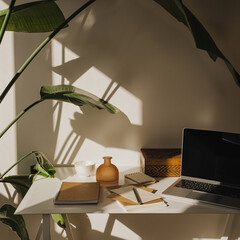 Creative workspace with laptop, notebooks and plant in natural light. Remote work or study concept