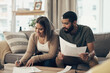 © N F/peopleimages.com - Home, couple and smile with signing documents for mortgage or loan agreement on sofa. Apartment, people and happy or satisfied with in living room with paperwork, form and contract for investment