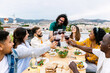 © Xavier Lorenzo - Young people celebrating together drinking red wine glasses on patio garden at summer party. Diverse friends having fun cheering glasses during dinner party. Friendship and celebration concept