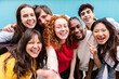 © Xavier Lorenzo - Diverse group of teenage student friends taking selfie portrait standing together over blue background. Youth and education concept