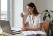 © Antonio Solano - Businesswoman drinking coffee and working on laptop at home office