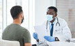 © peopleimages.com - Men, paperwork and doctor with mask, results or feedback for diagnosis, face cover or illness. People, medical or patient with professional, documents or conversation for healthcare, report or help