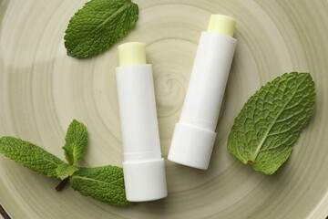 Sticker - Mint lip balms and green leaves on plate, flat lay. Cosmetic product