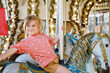 © Irina Schmidt - Happy positive preschool girl having a ride on the old vintage merry-go-round in city of St Malo France. Smiling child on a horse.