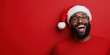 © Iona - A joyful man with a Santa hat and glasses laughs heartily against a bright red background, radiating holiday cheer and warmth.