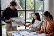 © Wasana - Asian business team analyzing financial documents in modern office