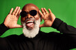 © peopleimages.com - Excited, black man and senior fun with green screen, sunglasses and fashion. Retirement, happy and comedy with funny, joke and elderly style with trendy, goofy and silly pose with studio background