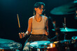 © Zamrznuti tonovi - Female drummer passionately playing drums on stage with dramatic lighting