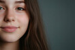 © Rohit k  - A close-up portrait of a young girl with long brown hair smiling softly against a neutral gray background, showcasing her natural beauty and youthful innocence