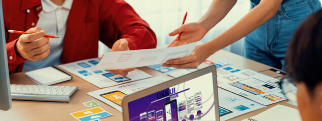 Panorama banner of startup UX developer or company employee design user interface or UI prototype for mobile application or website software with software display on laptop monitor in office. Synergic